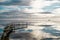 Relaxing view of a reflected blue sky with clouds, a ramshackle wharf and a fishing boat.