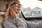 Relaxing on the way to the office. Attractive and stylish businesswoman in eyeglasses adjusting headphones while driving