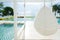 Relaxing white rattan hanging chair at swimming pool on sea view