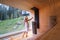 Relaxing Woman wrapped white towel in Hot Finnish sauna with huge wide window with green forest view pouring water on hot stones