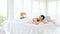 Relaxing young woman lying down and closed her eyes on massage beds at Asian luxury spa salon with white linen and wellness center