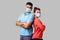 Reliable friendship. Cheerful young couple of friends with surgical medical mask standing back to back with crossed hands and