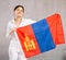 Reliant positive young woman holds big national flag of Mongolia with confident smile showing teeth.