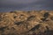 The relief of mountain hills at sunset illumination in the evening against the background of rain clouds