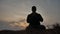 Religion concept. Silhouette of a male monk engaged in meditation lifestyle at sunset sunlight. Buddhist prayer at