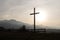 Religion theme, view of catholic cross silhouette, with fantastic sunset and mountains as background. Toned image