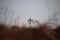 Religious background with blurred brown autumn grass and a cross further on.