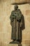 Religious bronze statue of a priest holding a cross at Caceres