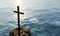 Religious christian cross standing on rock in the sea