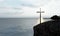 Religious christian cross standing on rock in the sea