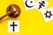 Religious conflict concept. World religions symbols near gavel on yellow background top view copy space