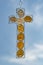 Religious cross of pebbles and wire mesh hanging in front of blue sky