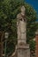 Religious statue in wooded gardens of condos under sunny blue sky at Montmartre in Paris.