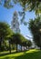 Religious tower with golden cupola under blue sky with tree alley in summer day