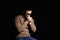 Religious young man praying to God on black background