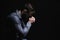 Religious young man praying to God on black background