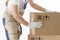 Relocation services concept. Mover`s hands In uniform carrying cardboard Box. Loader puts cardboard boxes