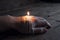 The remainder of a melted burning candle on a manâ€™s hand. Love has melted. Darkness. On wooden background