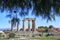 Remaining columns of the Temple of Apollo in ancient Corinth with mountains and village in background and view framed by pine tree
