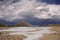 Remains of ice in the valley of the mountain river and beautiful clouds.