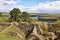 Remains of medieval castle building by the lake and fields