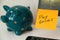 Reminder pay taxes sticked on monitor at freelancer`s workplace. Finance planning concept. Money-box for savings on background