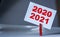 Reminder sticky note with clothes pin on table. Sticky note with crossed inscription 2020 and normal 2021. New Year 2021