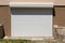 Remote controlled new modern white outdoor garage roll up doors mounted on newly built suburban family house side wall