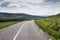 A remote and empty country side Irish road in county Kerry, with green fields and distant mountains