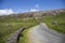 A remote and empty country side Irish road in county Kerry, with green fields and distant mountains