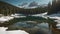 A remote mountain lake surrounded by snow-capped peaks and evergreen