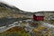 Remote  red wooden cabin in the rocky mountains on Lofoten in Norway next to a lake during a heavy storm and rain.