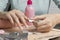 Removing gel Polish from nails. Woman pours remove liquid on a cotton pad, puts it on a nail and wraps the foil. Removing shellac