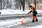 Removing snow from the sidewalk after snowstorm. A road worker with a shovel in his hands and in special clothes cleans the