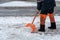 Removing snow from the sidewalk after snowstorm. A road worker with a shovel in his hands and in special clothes cleans the