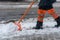 Removing snow from the sidewalk after snowstorm. A road worker with a shovel in his hands and in special clothes cleans the