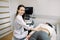 Renal ultrasound examination of kidneys in medical clinic. Smiling Caucasian woman doctor examines a young woman with