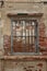 Rendered concrete wall with exposed red brick and wooden jail cell like window abstract