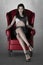 Rendering beautiful elegant vampire woman seated in a red chair