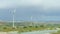 Renewable energy source, modern windmills spinning, green field, stormy horizon