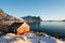 Renovated traditional red rorbu fishing hut on rocky coast near Reine on the Lofoten islands in Norway in winter with ocean and