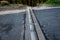 Renovation of asphalt road in the mountains. The ditches are filled with stones to slow down the water flowing out of the metal gr