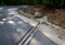 Renovation of asphalt road in the mountains. The ditches are filled with stones to slow down the water flowing out of the metal gr