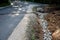 Renovation of asphalt road in the mountains. The ditches are filled with stones to slow down the water flowing out of the metal gr