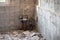 Renovation in an old room, dismantled floor tiles, concrete walls, plumbing elements, construction debris