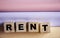 RENT word on wooden cubes on a pink lilac and beige. Real estate business concept