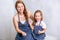 Repair in the apartment. Happy family mother and daughter in aprons paint the wall with white paint. Mother and daughter smeared e