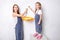 Repair in the apartment. Happy family mother and little daughter in blue aprons paints the wall with white paint