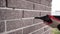 Repair in apartments and houses concept. The master sews seams on the brickwork. Joints in brickwork. Grouting with