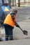 Repair of city roads and replacement of worn asphalt concrete pavement. A worker with a shovel throws concrete into a pit to